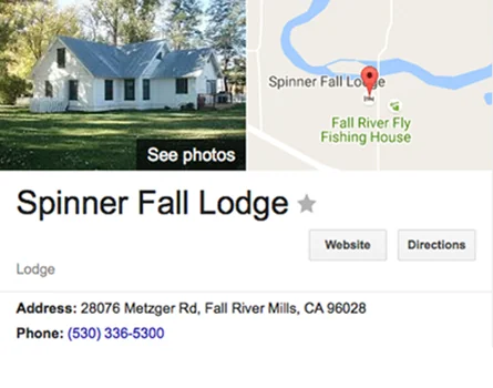 White farmhouse with dark roof surrounded by trees and green lawn, labeled Spinner Fall Lodge