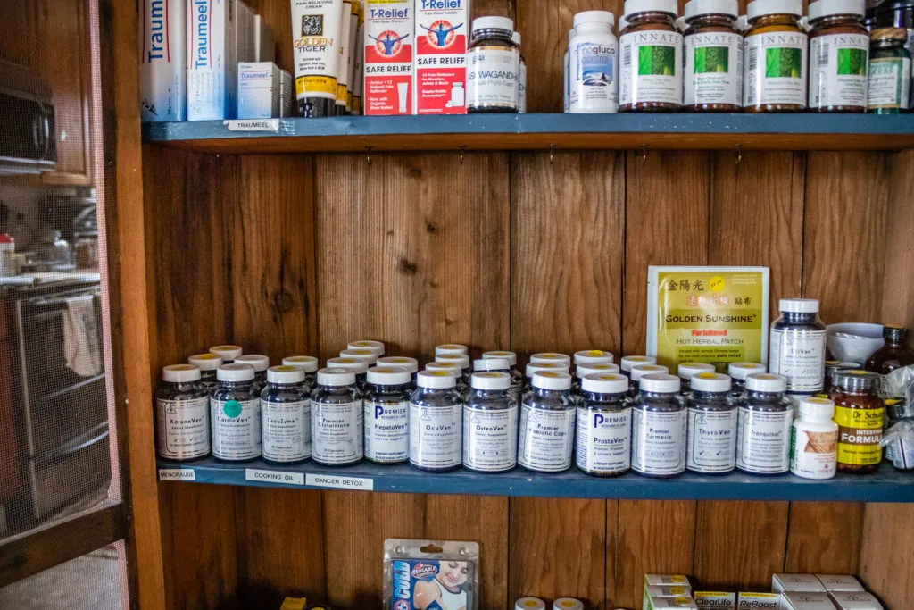 Wooden cabinet shelving displaying bottles of supplements and health products organized on multiple tiers