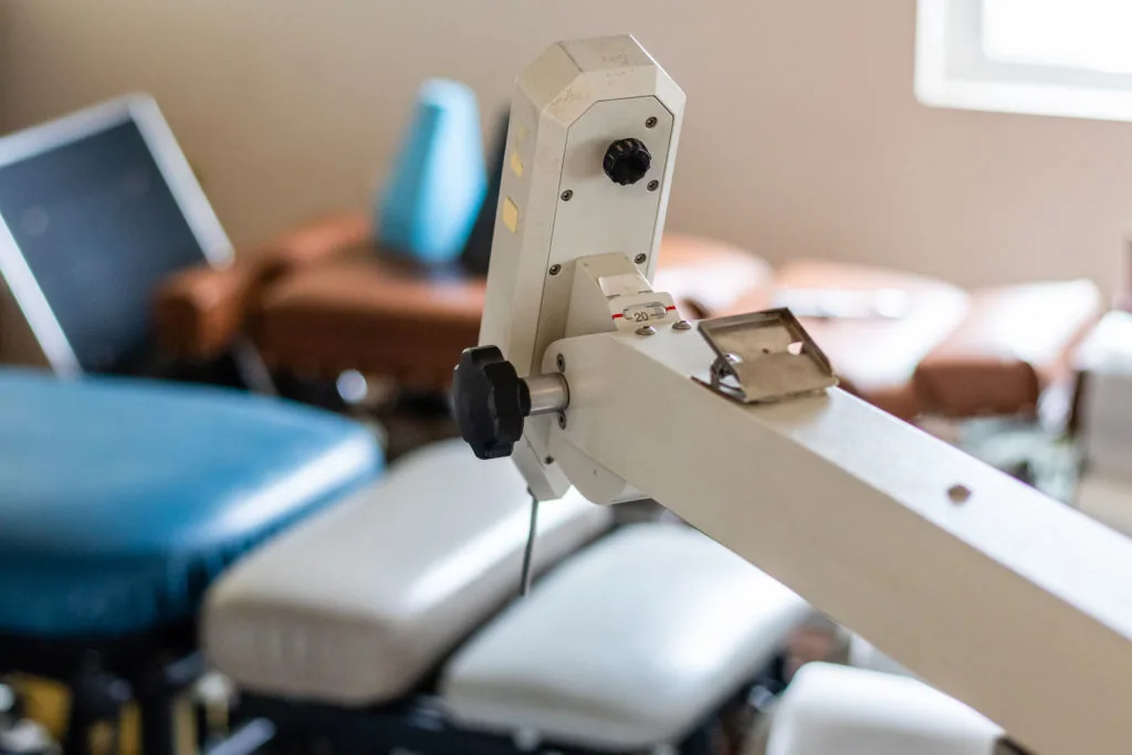 Chiropractic adjustment device with white frame and black knob on clinical examination table