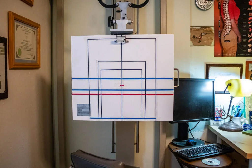 Vision training apparatus with concentric squares and center crosshair mounted on wall above desk with monitor and keyboard