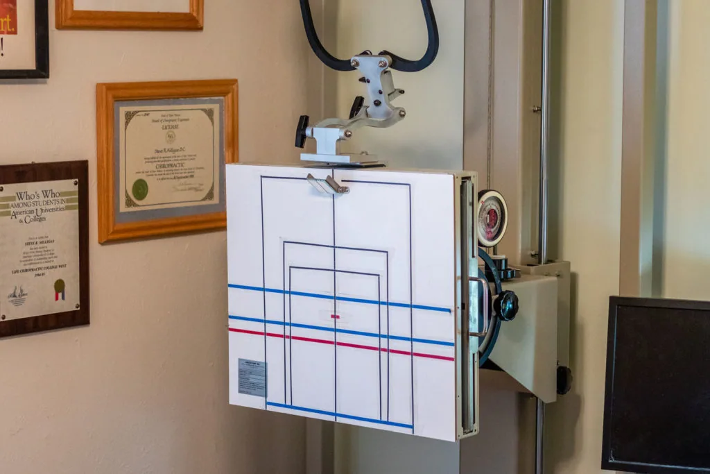 Optics testing equipment with mounted binocular microscope above a chart displaying blue and red grid lines on wall in professional office