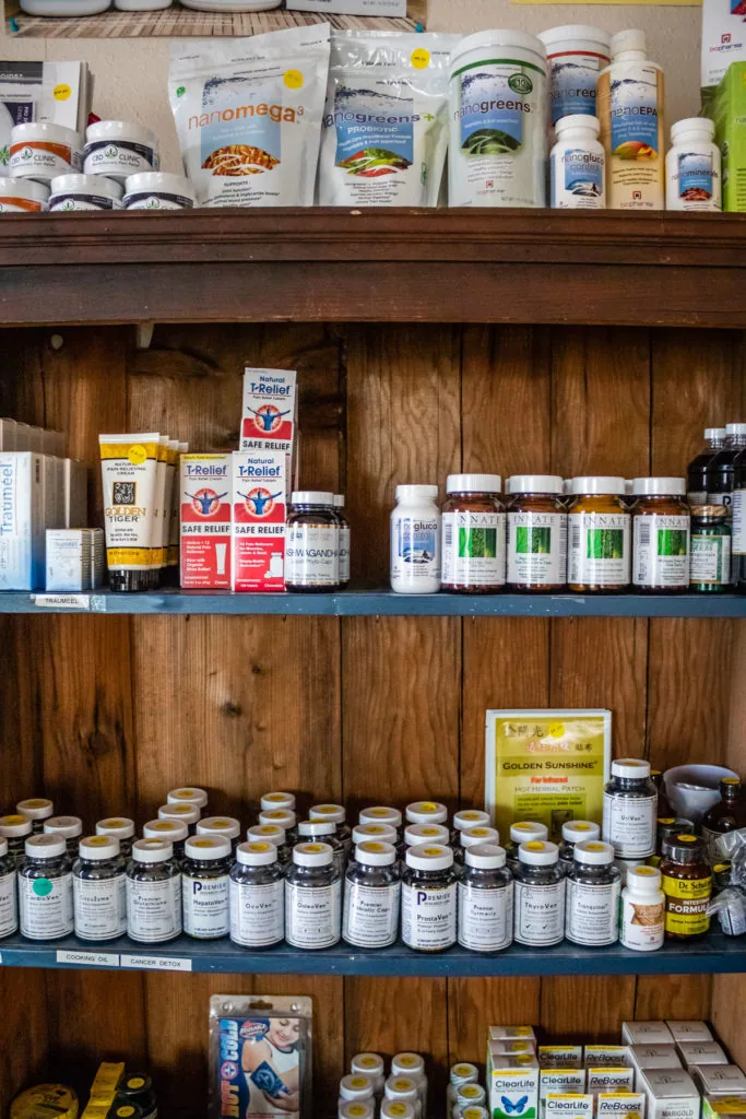 Wooden shelving unit displaying dietary supplements, vitamins, and health products in bottles and containers organized across four shelves.