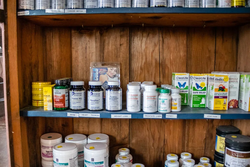 Wooden cabinet shelves stocked with various bottles, jars, and containers of supplements and health products