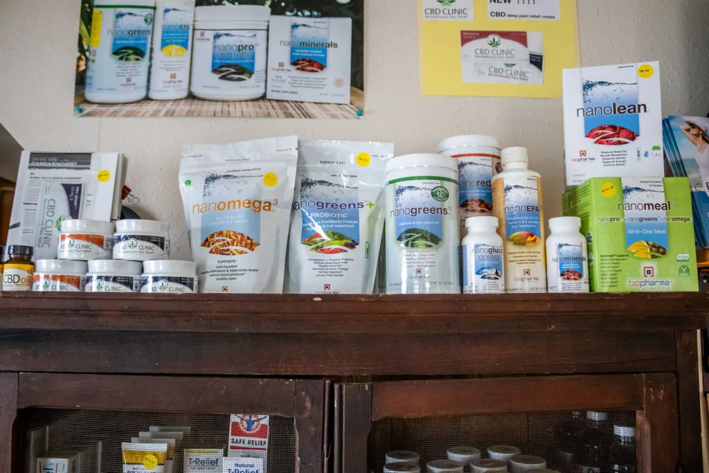 Health supplement and wellness product display on wooden shelf and wall, featuring various bottles, packets and containers with nano-formulated products