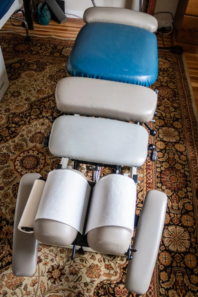 Leg press exercise machine with blue and white padded cushions on ornate carpet