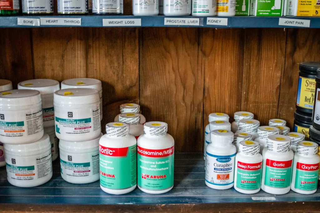 Shelves stocked with various supplement bottles and containers organized by health category labels.