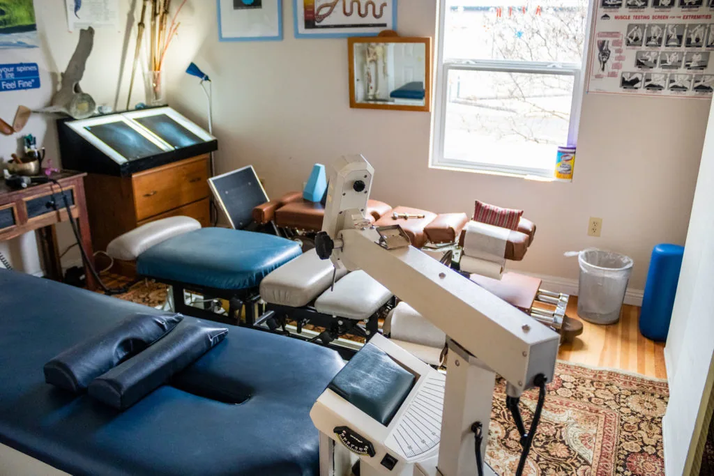 Chiropractic treatment room with examination tables, medical equipment, and adjustment devices