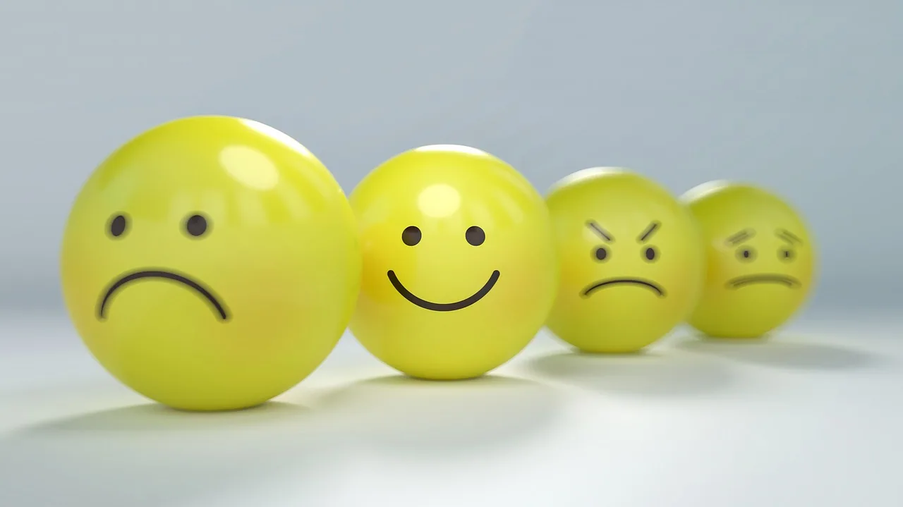 Four yellow spheres with drawn faces showing sad, happy, angry, and worried expressions arranged in a row